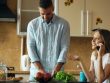 Attractive couple in the kitchen early morning. Beautiful girl chatting phone while her boyfriend cooking breakfast at home