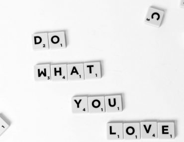 Scrabble tiles spelling 'Do What You Love' on a white background, encouraging creativity.