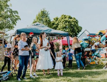 A lively outdoor gathering with families enjoying balloons and a sunny day.