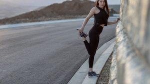 woman in black tank top and black leggings walking on gray concrete road during daytime